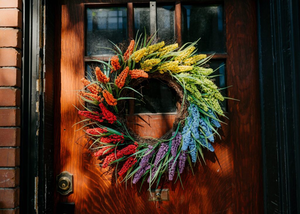 Decorative wreath on a door, comprised of flowers in a rainbow pattern